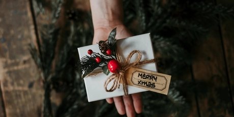 Hand mit einem verpackten Weihnachtsgeschenk