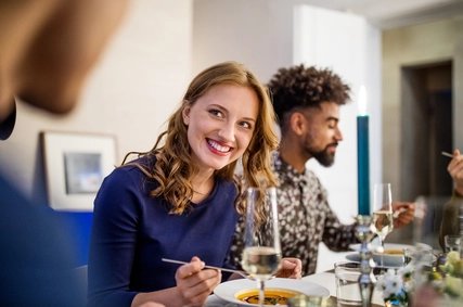 Beautiful woman having food with friends at dining table