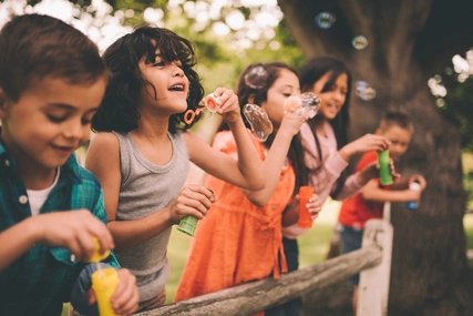 Kinder spielen mit Seifenblasen