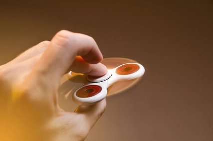 Red and white Fidget Spinner spinning in one hand close up 