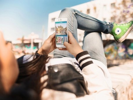 Junge Frau nutzt Streetart Highlight der ABOUT BERLIN App.