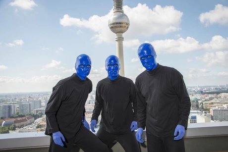 Die BLUE MAN GROUP posiert vor dem Fernsehturm bei strahlend blauem Himmel.