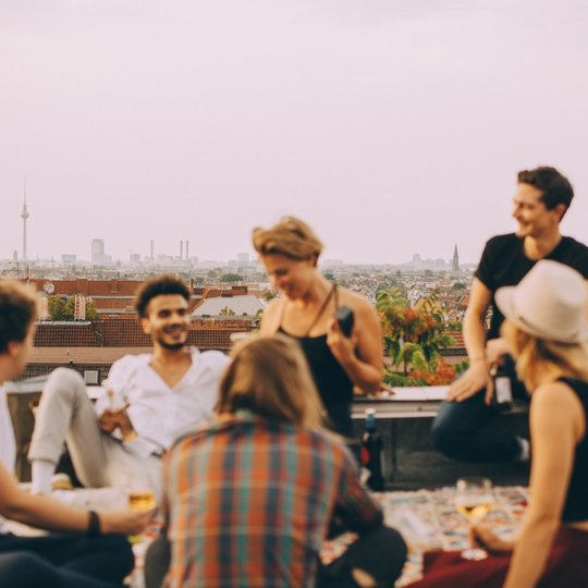 Freunde treffen sich über den Dächern Berlins, lachen zusammen und haben spaß