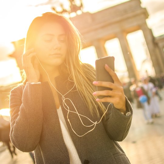 Junge Frau hört Audiotour am Brandenburger Tor.
