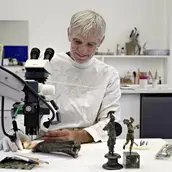 Restaurator Uwe Peltz bei der Reinigung einer römischen Bronzestatuette der Minerva von Korrosion.