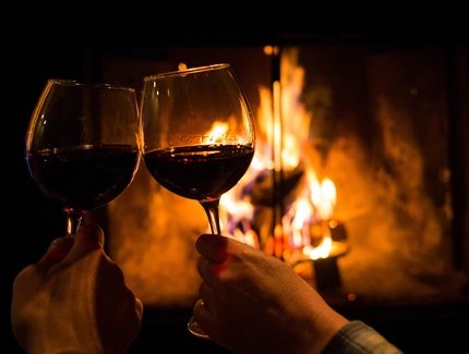Couple holding pair of glasses with wine at fire pit