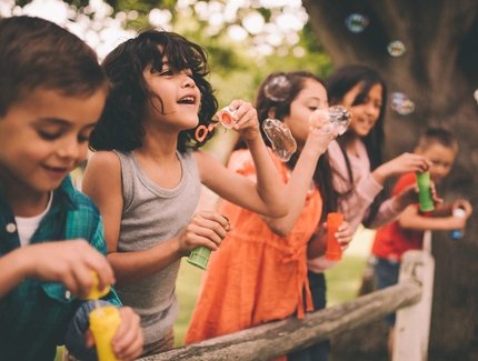 Kinder spielen mit Seifenblasen