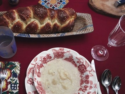Overhead shot of a table with a loaf of challah and a plate on it.